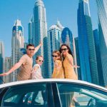 Family posing on a car in front of the Dubai Skyline in a blog about family travel that includes a section about travel to the middle east