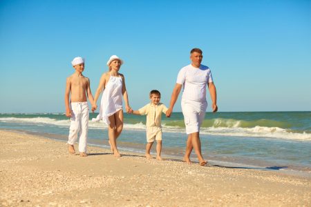A family of four walking on the beach added to a blog post about family travel including safari and beach holidays