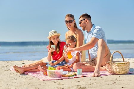 Family on the beach as on vacation or holiday stock image used in a blog post listing 10 tips to help plan a family vacation