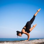 Strength yoga pose on a mountain with blue sky in the background