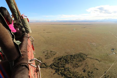 The view from a hot air balloon over the Masaai Mara showing the wild grassland and bush below the basket.